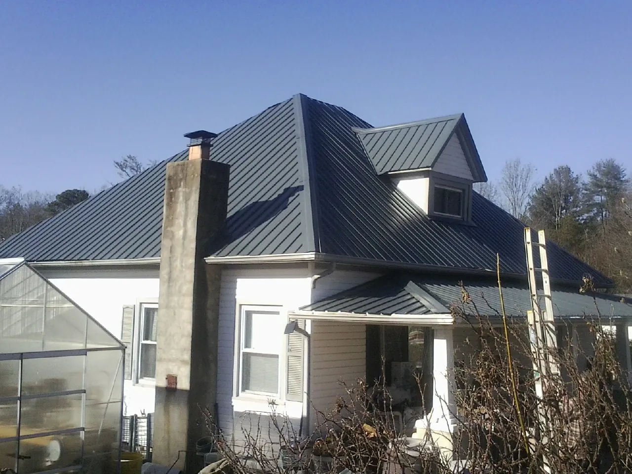 Dark blue standing seam metal roof on a white farmhouse with dormer — Slate & Tile Roof Repair by Roofing Brothers in South Pasadena