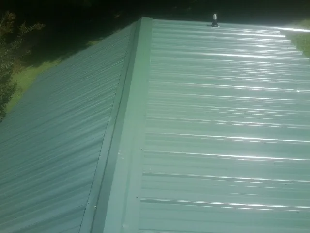New green metal panels meeting at the ridge of a roof — Flat Roof Repair work by our crew in South Pasadena