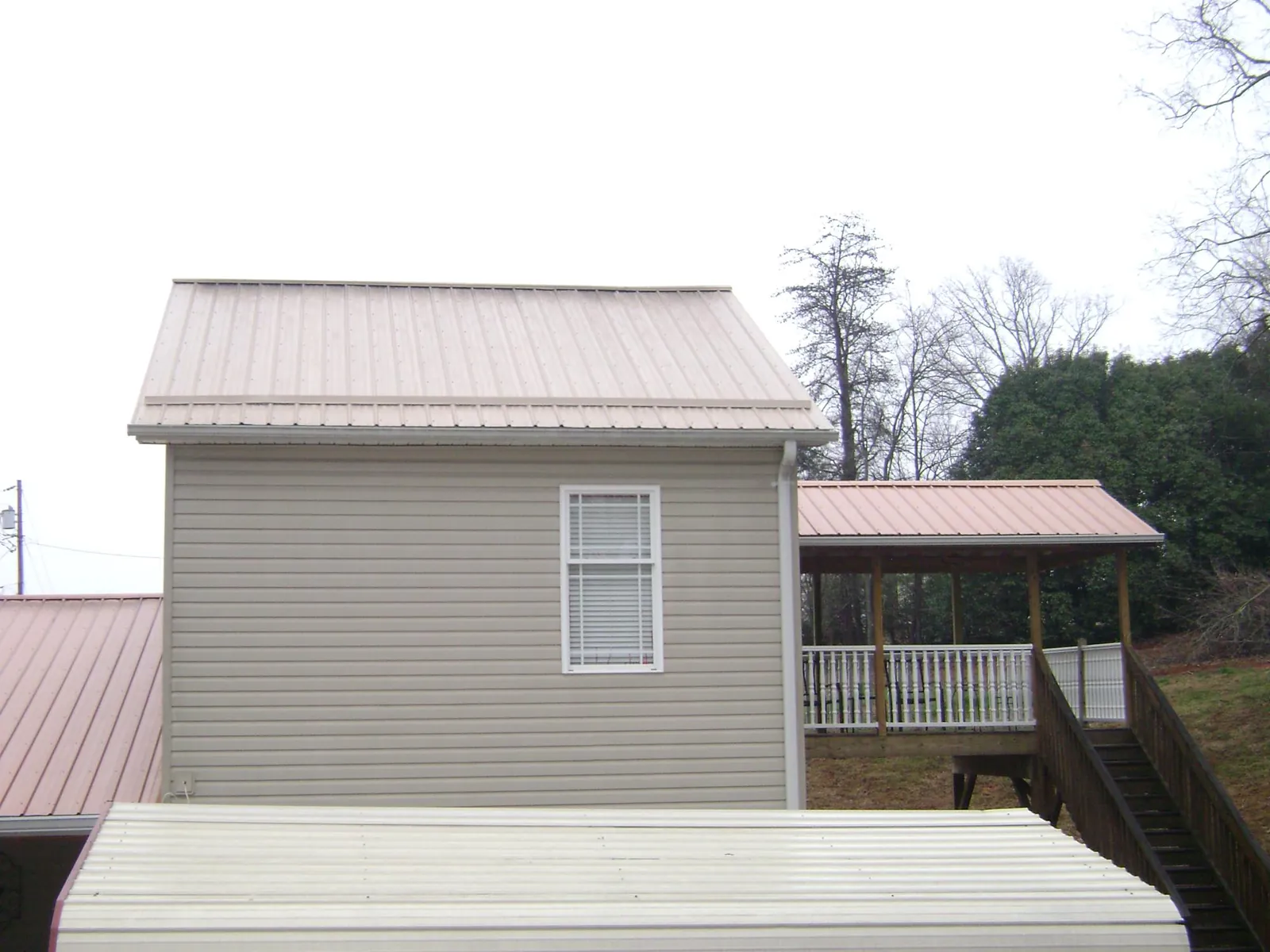 Tan metal roofs on a two story addition and attached porch, from a Roof Replacement job in South Pasadena